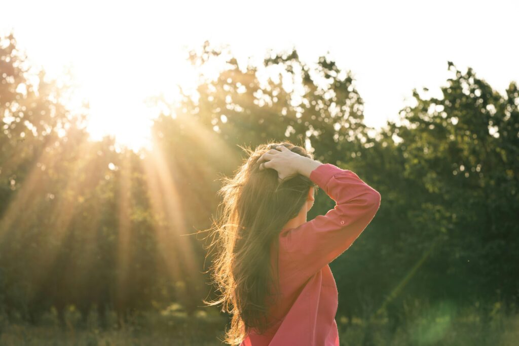 woman calming her nervous system in nature under rays of sun